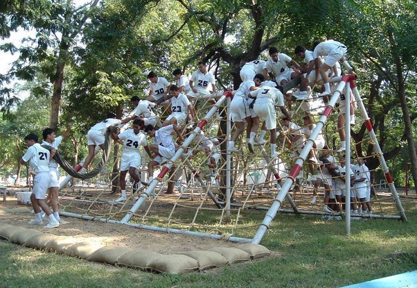 Candidates completing spider web obstacle in snake race.